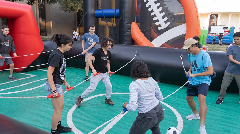 Students inside an inflatable rectangle kicking a soccer ball around