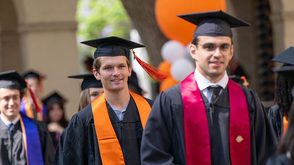 Caltech graduates enter their commencement ceremony wearing caps and gowns