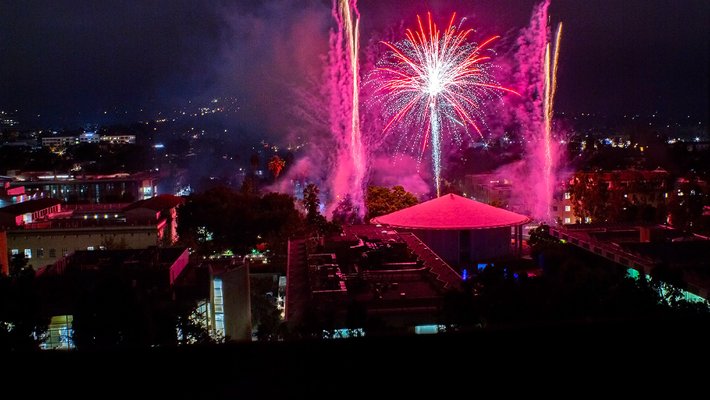 Red and pink fireworks light up the night sky over Beckman Auditorium