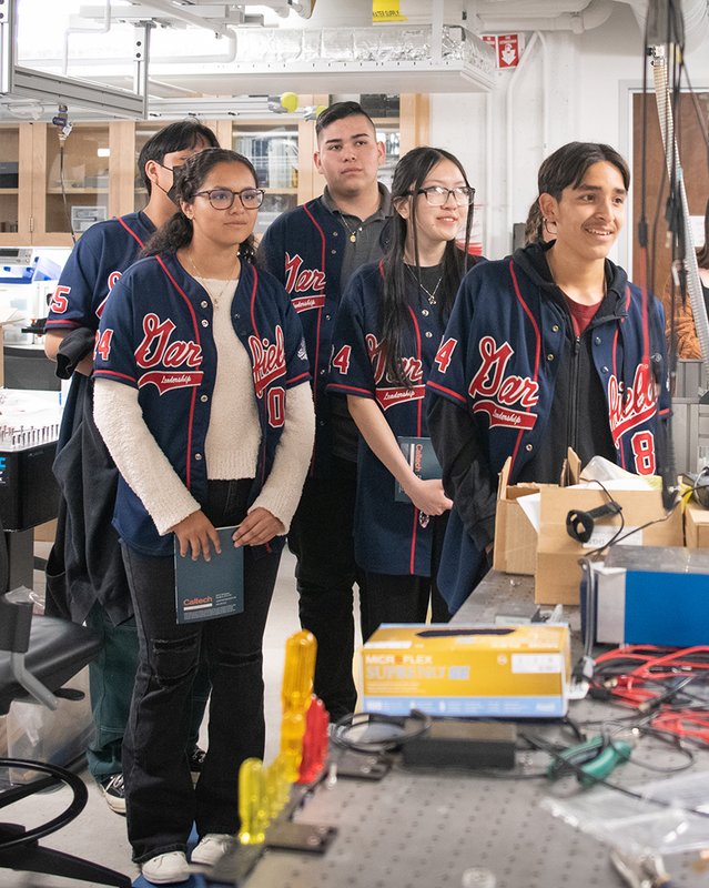 In a laboratory, five people in Garfield High School jackets look to the right of the camera.
