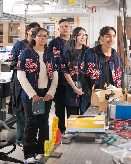 In a laboratory, five people in Garfield High School jackets look to the right of the camera.