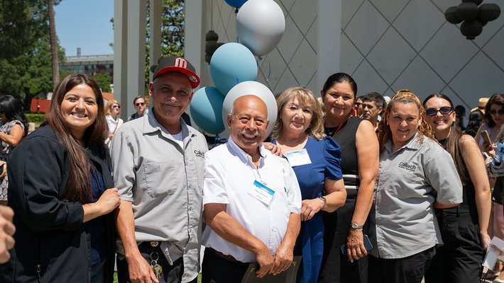 A line of people stand in the sunshine outside Beckman Auditorium following the 2025 Staff Service Awards