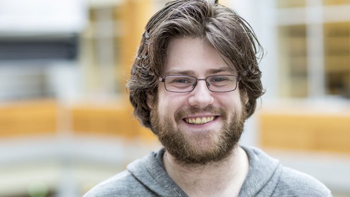 Portrait of Caltech professor Adam Blank wearing glasses and a gray hooded sweartshirt