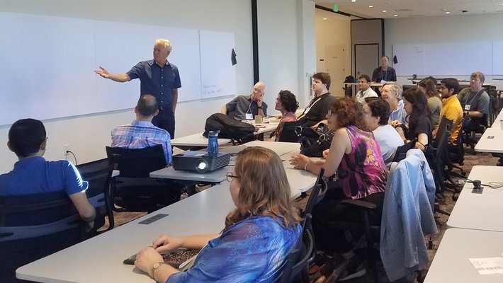 students in classroom with professor at whiteboard