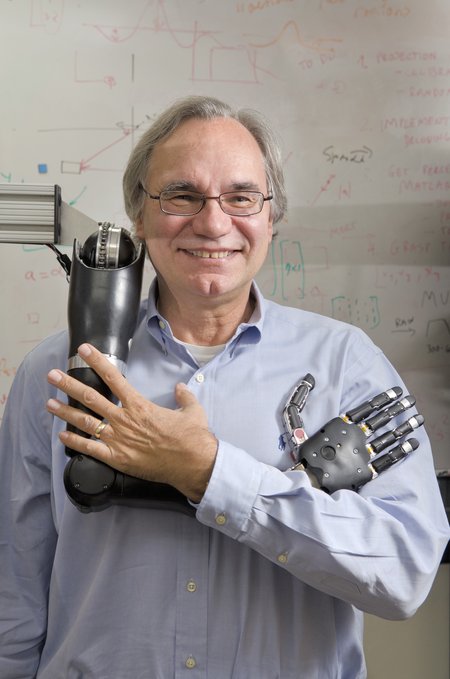 Image of Richard Andersen, neuroscientist, holding a robotic arm