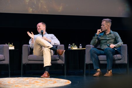 Cameron Hummels listens as Elias Most speaks during a panel on stage