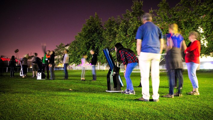 Visitors look through telescopes during a Caltech astronomy outreach event on the grass outside Cahill.