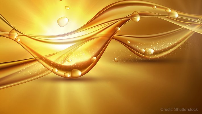 An abstract conceptual image featuring a wavy liquid with some drops and sunlight in the background.