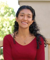 A portrait of Azita Emami. She is wearing a sweater and smiling.