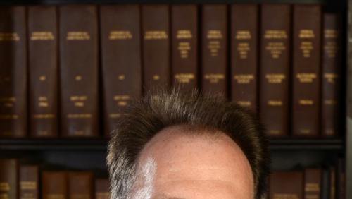 Brian Stoltz in front of a bookshelf.