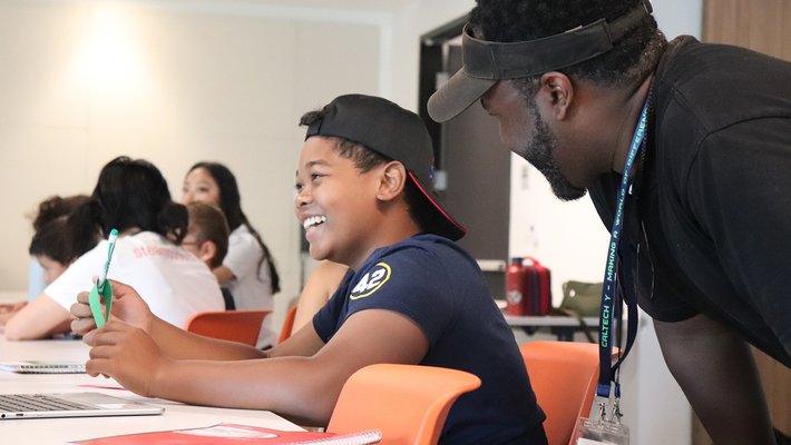 A person leans over a smiling child seated at a table