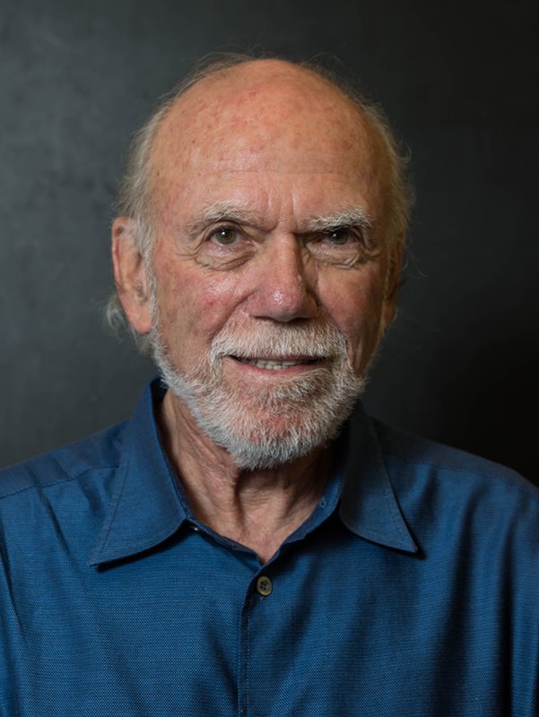 Portrait of Barry Barish. He wears a navy blue shirt and has a white mustache and beard.