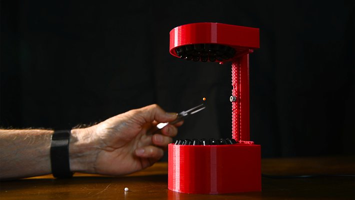 A hand places a pellet into a 3D-printed ultrasonic levitator.