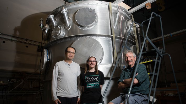 Members of the nEDM team stand in front of their magnetic cryovessel experimental apparatus