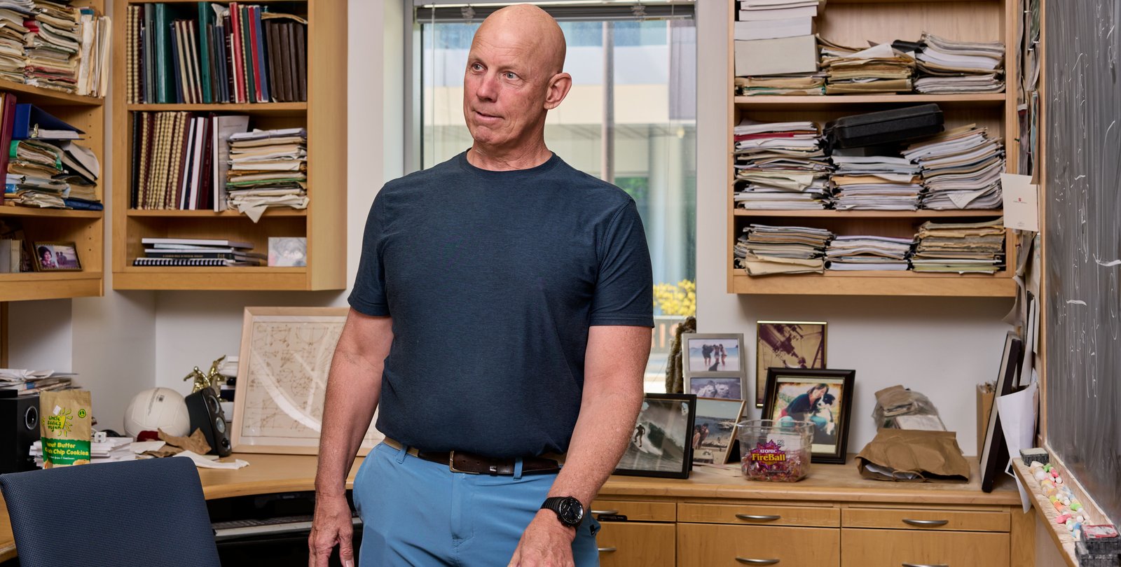 Image of Rob Philiips leaning against a desk with shelves of books behind him