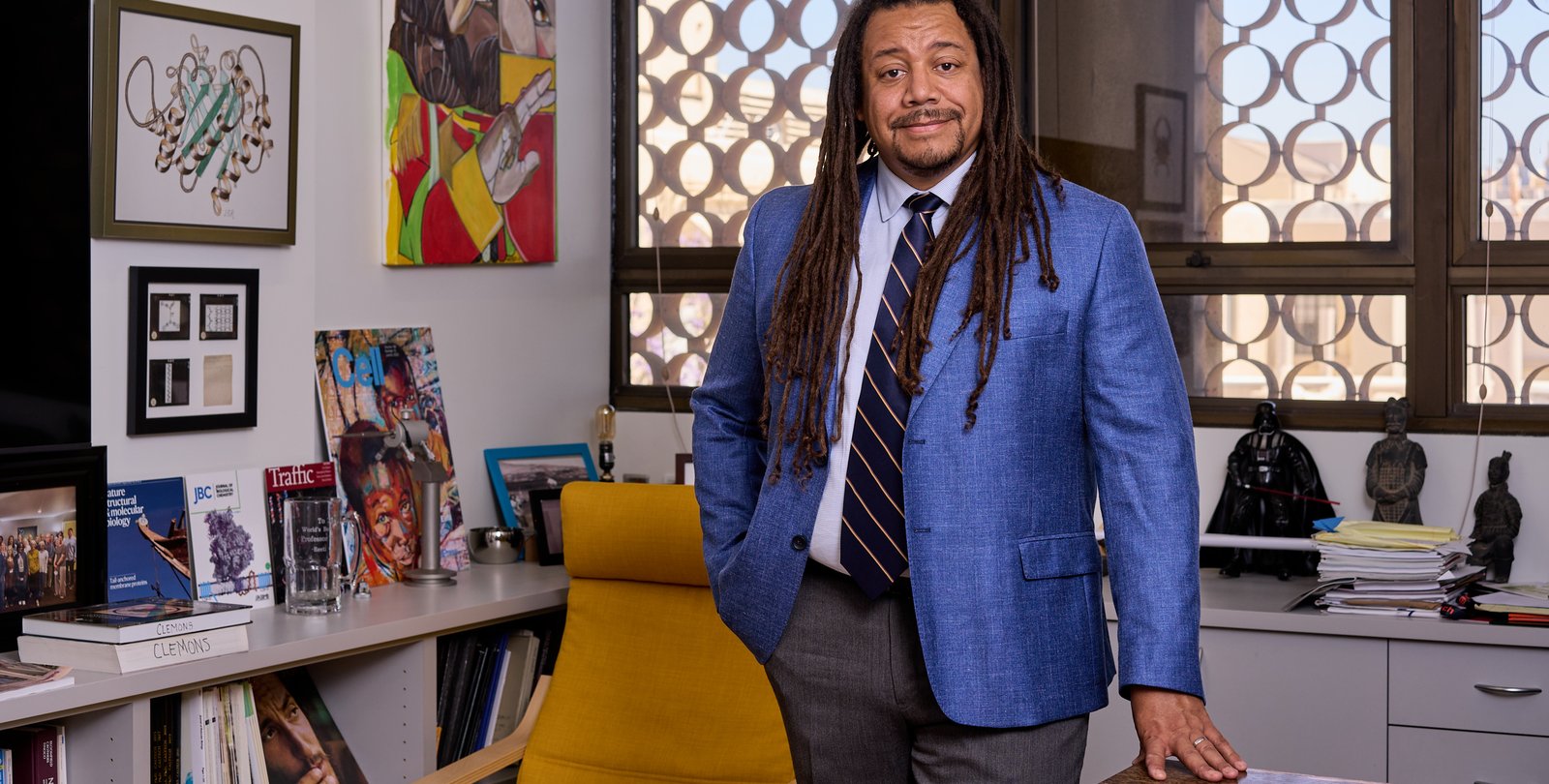 Bil Clemons in blue blazer standing next to desk in his office