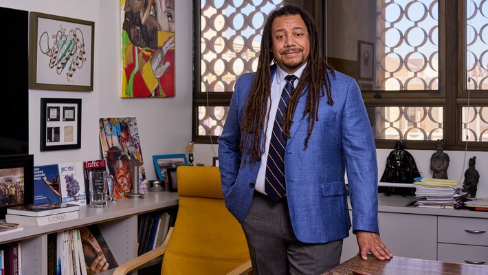 Bil Clemons in blue blazer standing next to desk in his office