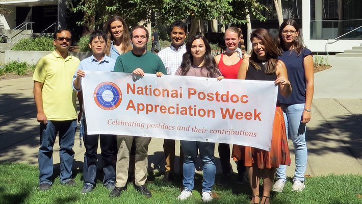 members of the Caltech Postdoc Association hold a banner for Postdoc Appreciation Week.