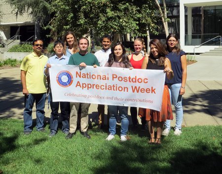 members of the Caltech Postdoc Association hold a banner for Postdoc Appreciation Week.