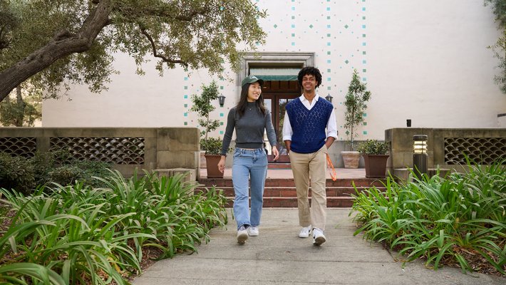 A male and female student walking toward the camera