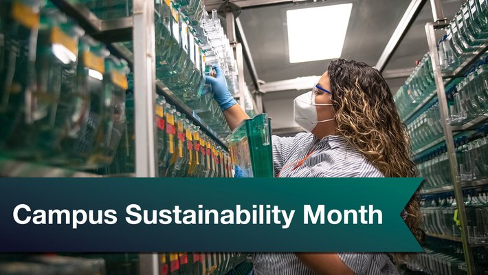 A digital banner reads "Campus Sustainability Month" in front of a person in a laboratory