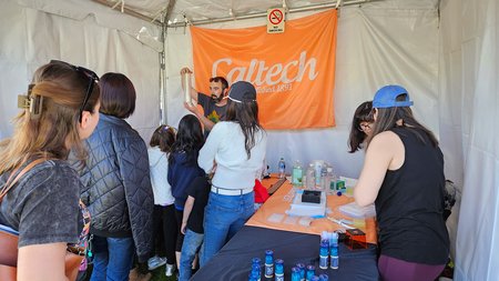 Alex Johnson explains scientific equipment to guests at Caltech's booth.