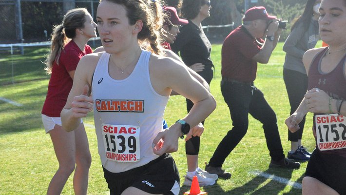 Graduate student Margaret Trautner running in white jersey and black shorts