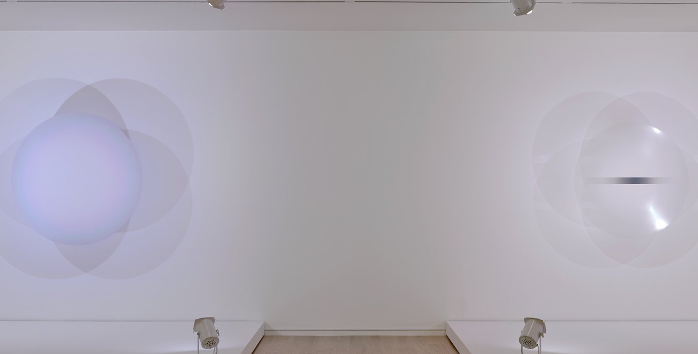 an art installation showing two large circular lights mounted on the wall next to one another