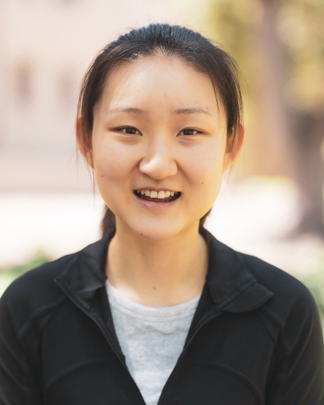 A young woman wearing a black jacket and gray shirt.