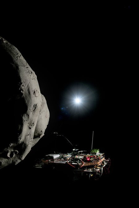a model comet with a robotic spacecraft floating beside it and a bright light above