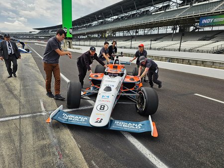 several people pushing Caltech's autonomous IndyCar into position on a race track.