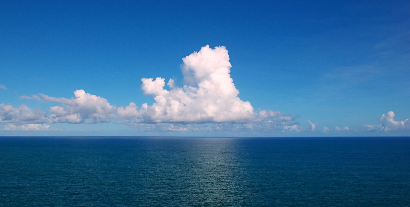A photo of clouds lingering over an expanse of ocean.