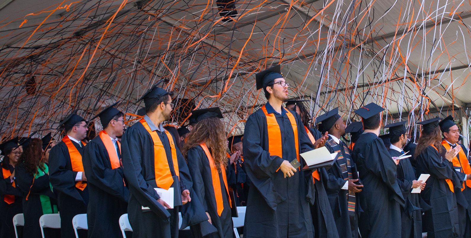 Orange, black, and white confetti falls on Caltech's newest graduates who are wearing their caps and gowns