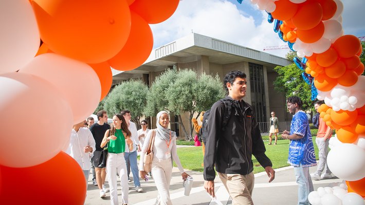 Students walk under a balloon arch into Convocation
