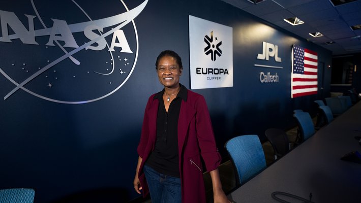 Image of Tracy Drain in front of a wall that reads NASA JPL Caltech