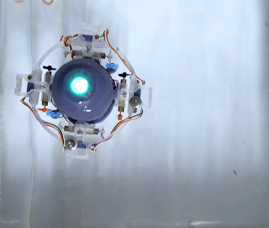 A small underwater robot is shown with one central bluish light shining.