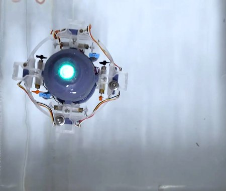 A small underwater robot is shown with one central bluish light shining.