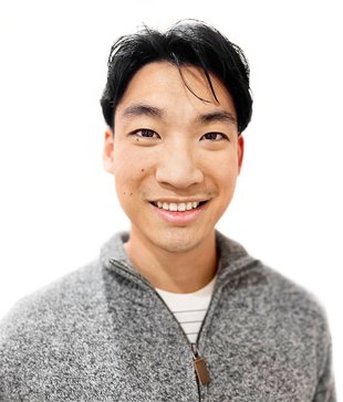 Portrait of Daniel Tang. He wears a gray sweater and has short black hair.