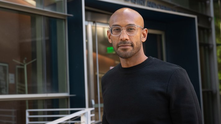 a portrait of Sujit Datta with an academic building behind him