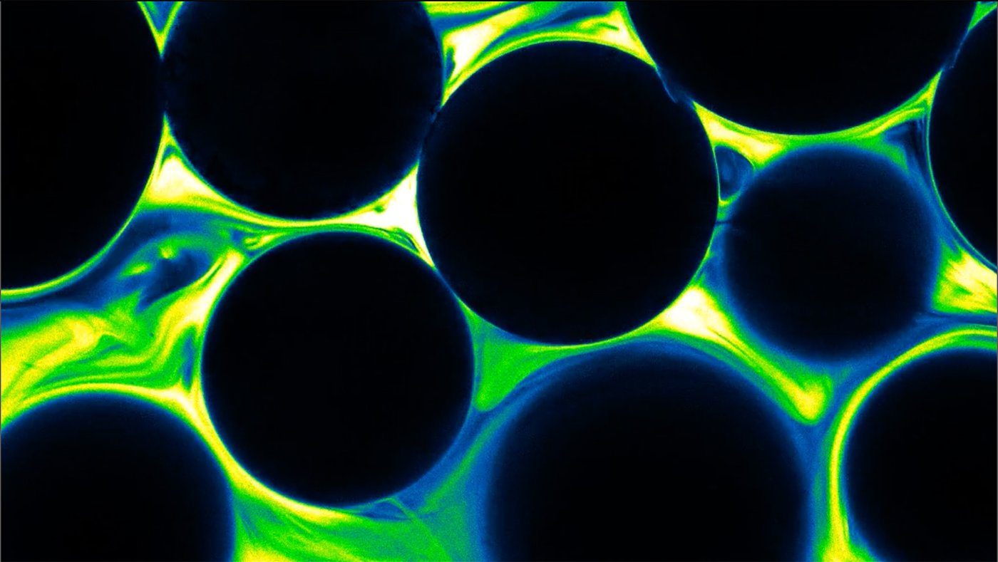 dark circles surrounded by glowing green and blue fluid