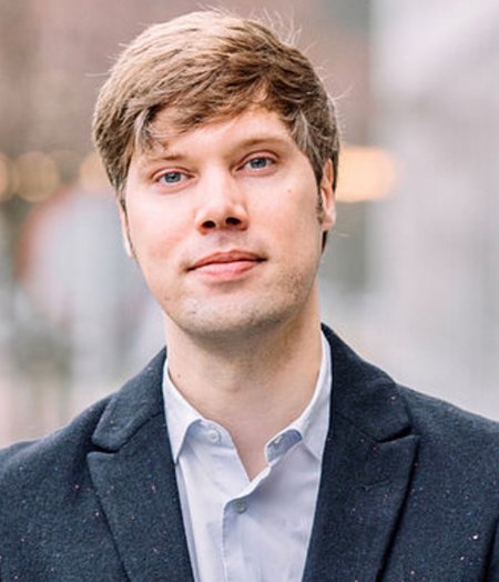 Headshot of a person with blonde hair in a shirt and jacket