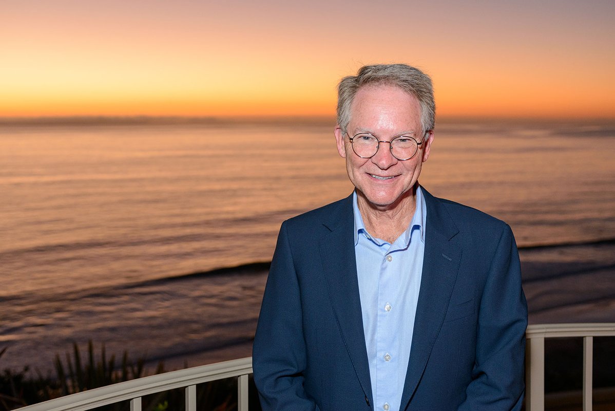 Cropped photo of man in blazer in front of a sunset