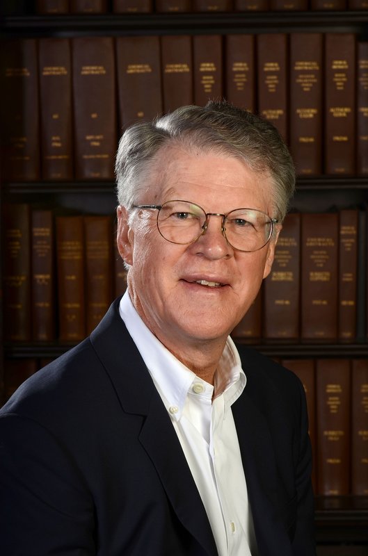 A portrait of Peter Dervan in front of a book case.