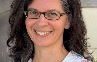 Portrait of Dianne Newman. She has long dark hair and wears glasses. She is smiling and wearing a flowered shirt.