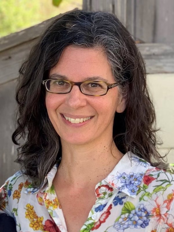 Portrait of Dianne Newman. She has long dark hair and wears glasses. She is smiling and wearing a flowered shirt.