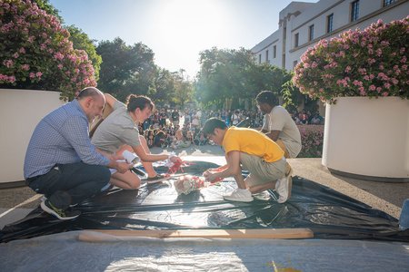 Michael Mello, faculty judge for the Egg Drop Competition, examines a fallen egg with students.