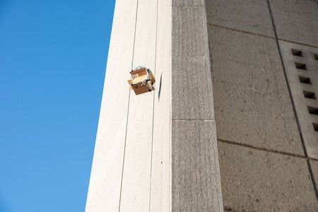 An egg falls from the top of Caltech Hall inside a protective cardboard shell.