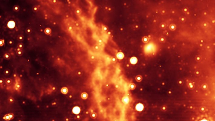 Astronomical image of the Double Helix Nebula in the Milky Way Galaxy. The nebula appears as two twisting ropes in orange surrounded by stars appearing as orange spots.