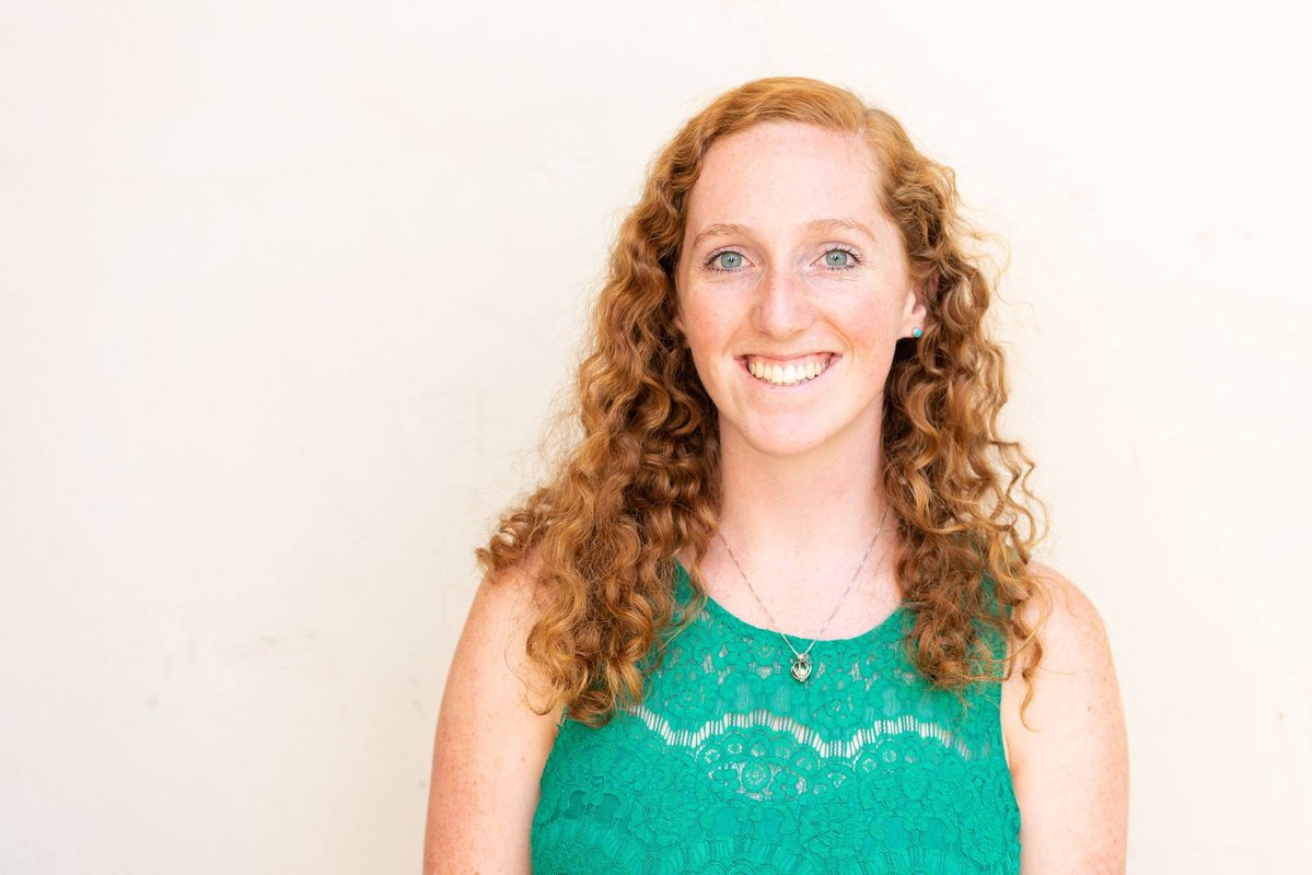 Smiling portrait of graduate student Jackie Dowling in a teal top against a white background