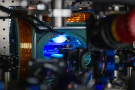 A chamber with blue light is surrounded by optical equipment.